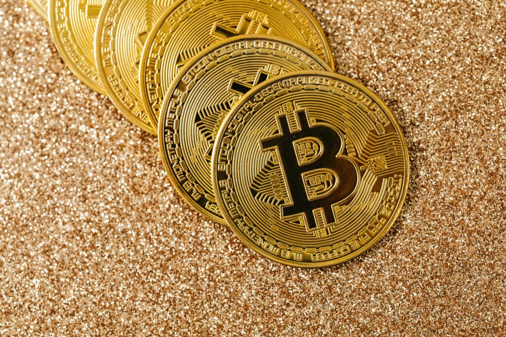 Golden Bitcoin coins arranged on a sparkling glitter surface, symbolizing cryptocurrency and wealth.